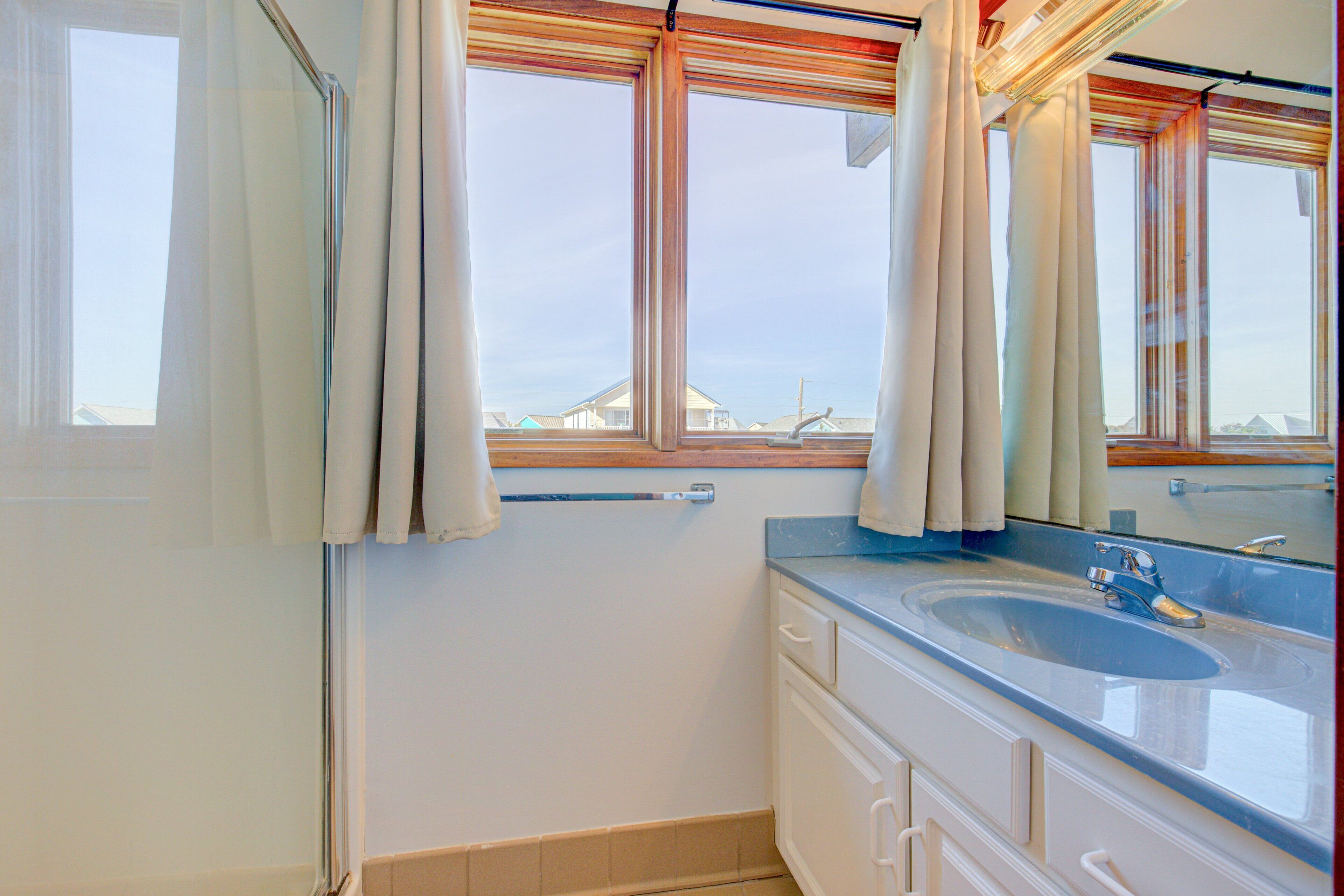 Une salle de bain avec une grande fenêtre, un lavabo et un miroir.