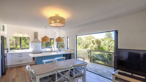Une cuisine moderne avec des meubles blancs, un grand îlot central et un coin repas doté de chaises blanches.