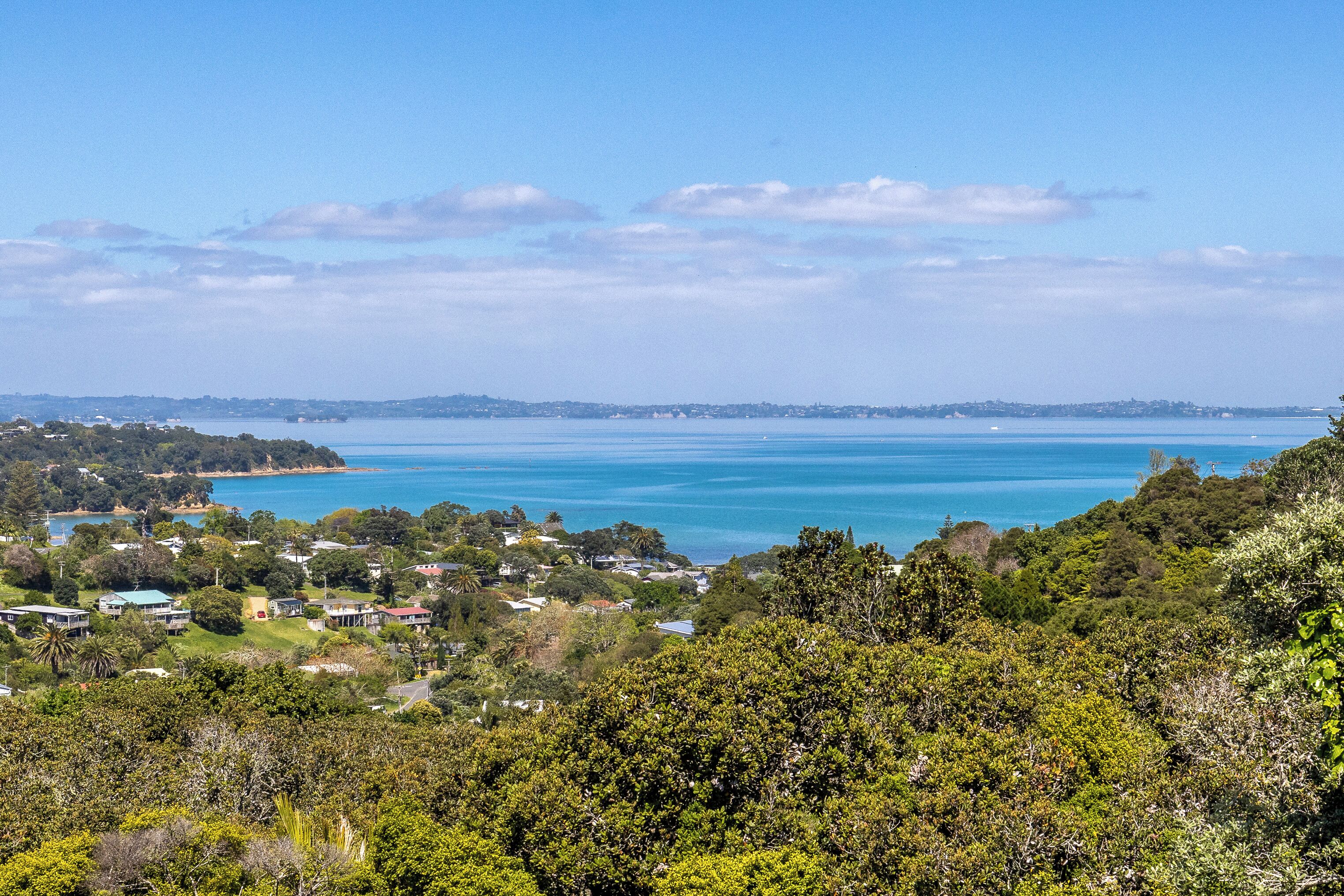 A coastal landscape with a view of the sea and a residential area with houses and greenery.