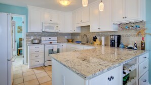 A kitchen with white cabinets, a granite countertop, a microwave, a stove, and hanging pendant lights. - Dog-friendly oceanfront home with beach access, a washer/dryer & central AC (Surf City)