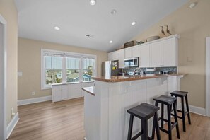 Una cocina con gabinetes blancos, encimera de granito y microondas integrado.