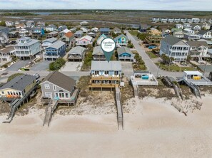 Vista aérea de una zona residencial costera con varias casas, algunas con terrazas y acceso a la playa.