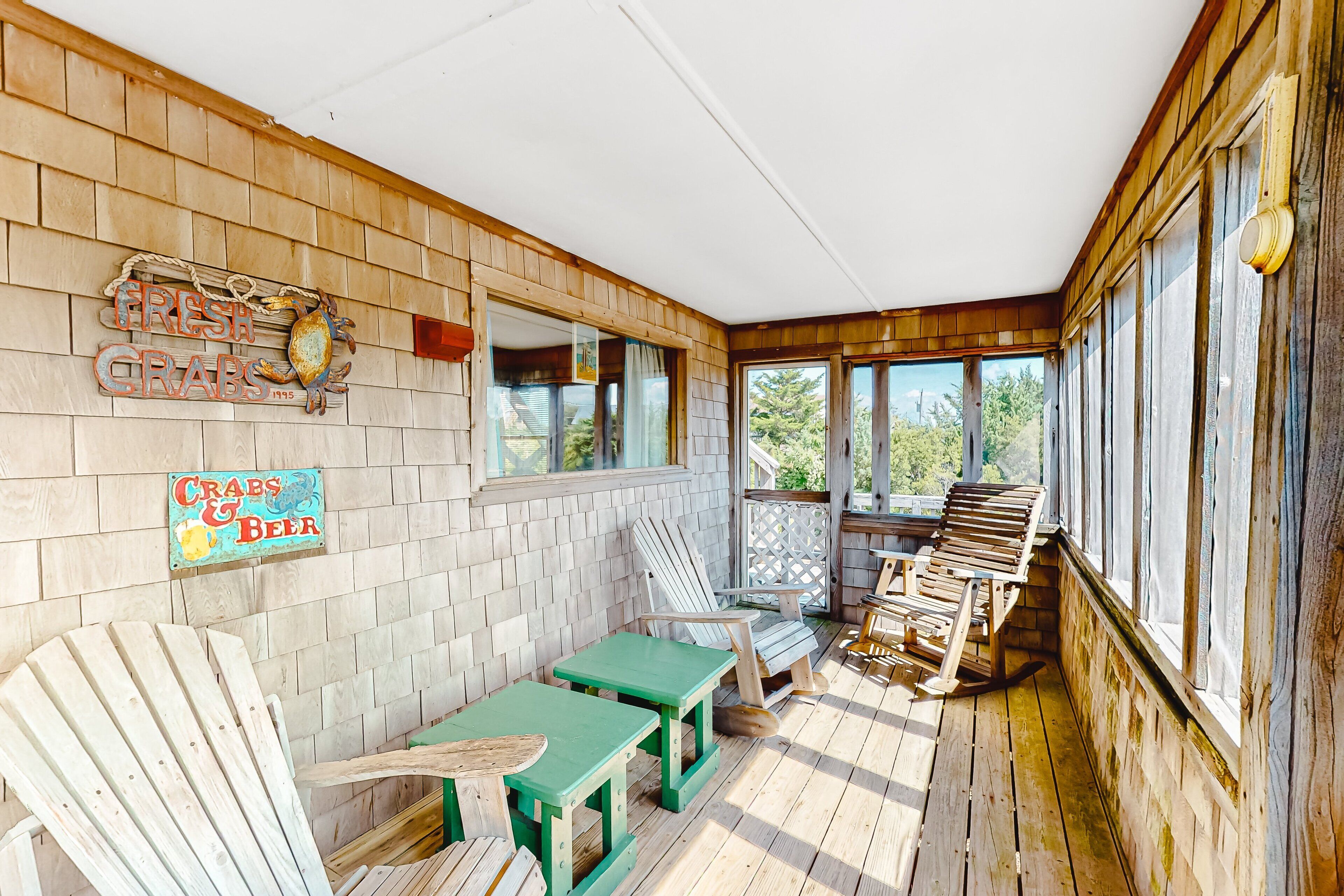 Een houten veranda met een bank, stoelen en een tafel.