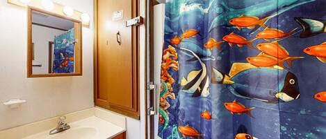 Une salle de bain avec un lavabo, un miroir et un rideau de douche orné de motifs de poissons.