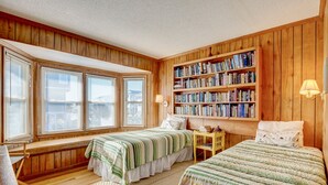 A room with two beds, a bookshelf, and a window with blinds. - Oceanfront Home w/Incredible Views, Private Boardwalk to the Beach, & Free WiFi (Holden Beach)