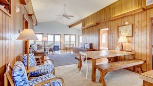 A spacious room with wooden walls, a large dining table, and comfortable seating. - Oceanfront Home w/Incredible Views, Private Boardwalk to the Beach, & Free WiFi (Holden Beach)
