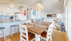 Een ruime keuken met witte kastjes, een houten eettafel en een kroonluchter.