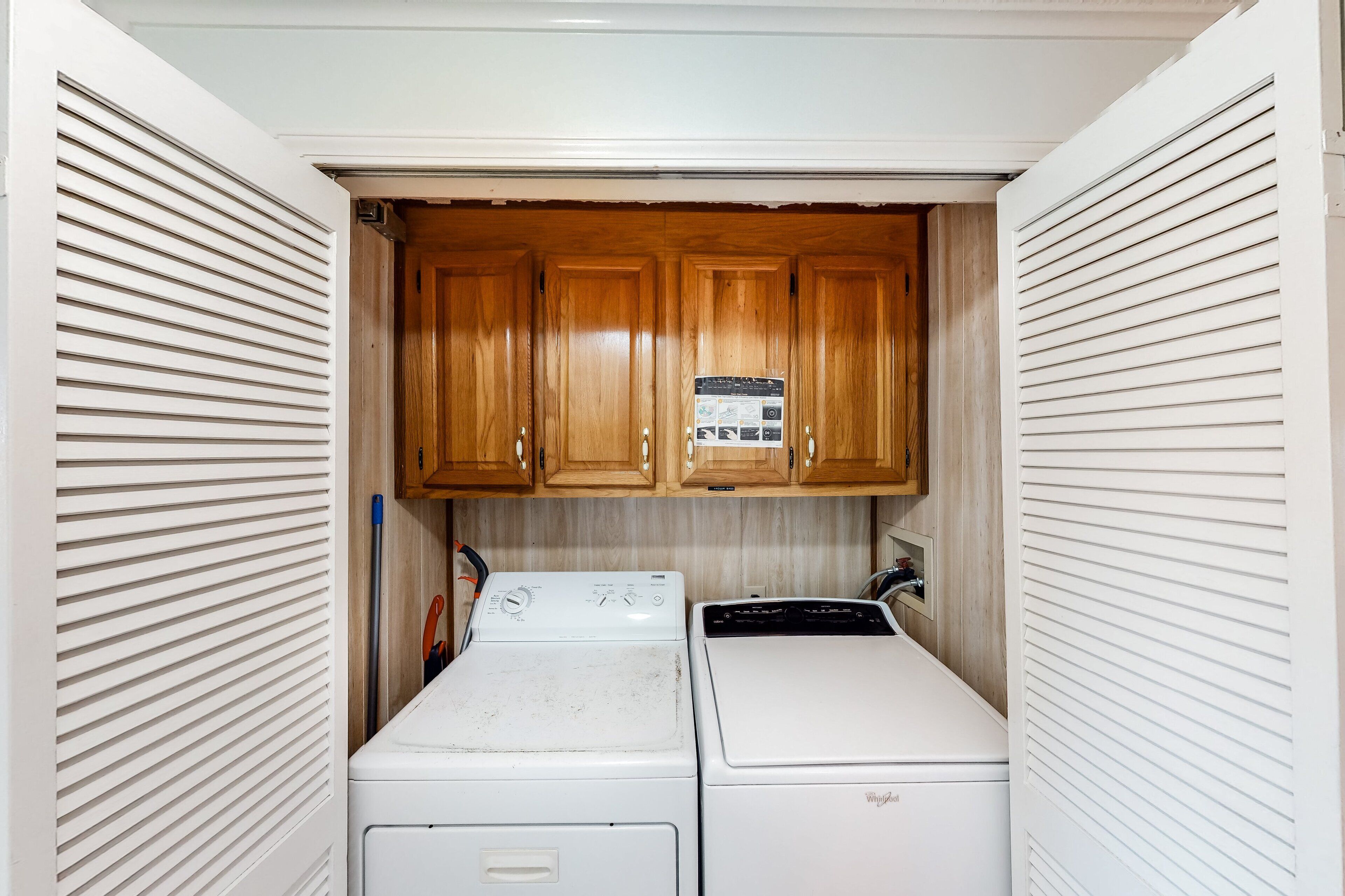 A laundry room with a washer and dryer, wooden cabinets, and a utility wall.