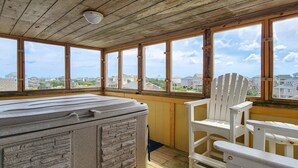 Eine Holterrasse mit Whirlpool, weißen Adirondack-Stühlen und großen Fenstern mit Blick auf Häuser.