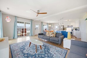 A spacious living area with a sofa, coffee table, and patterned rug. - Bright coastal getaway in Surf City with ocean views & a quick walk to beach access! (Surf City)
