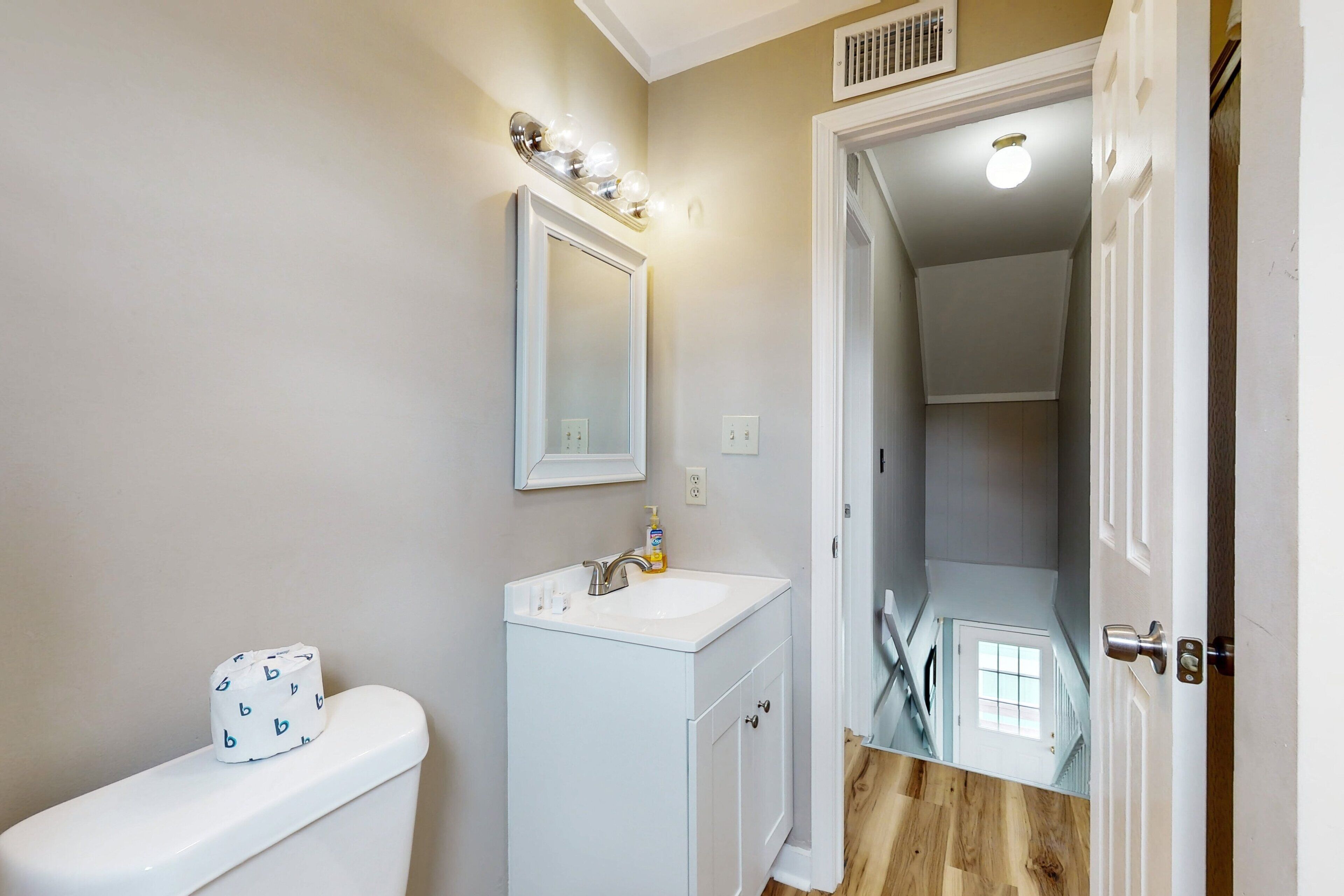 A bathroom with a toilet, sink, and mirror.
