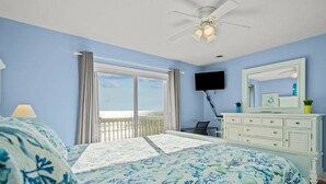 Ein Schlafzimmer mit Bett, Deckenventilator, Fernseher, Kommode und Meerblick.