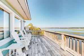 A wooden deck with white chairs and a railing overlooking a body of water. - Sound front retreat with easy beach access, sauna and private dock for your boat! (Surf City)