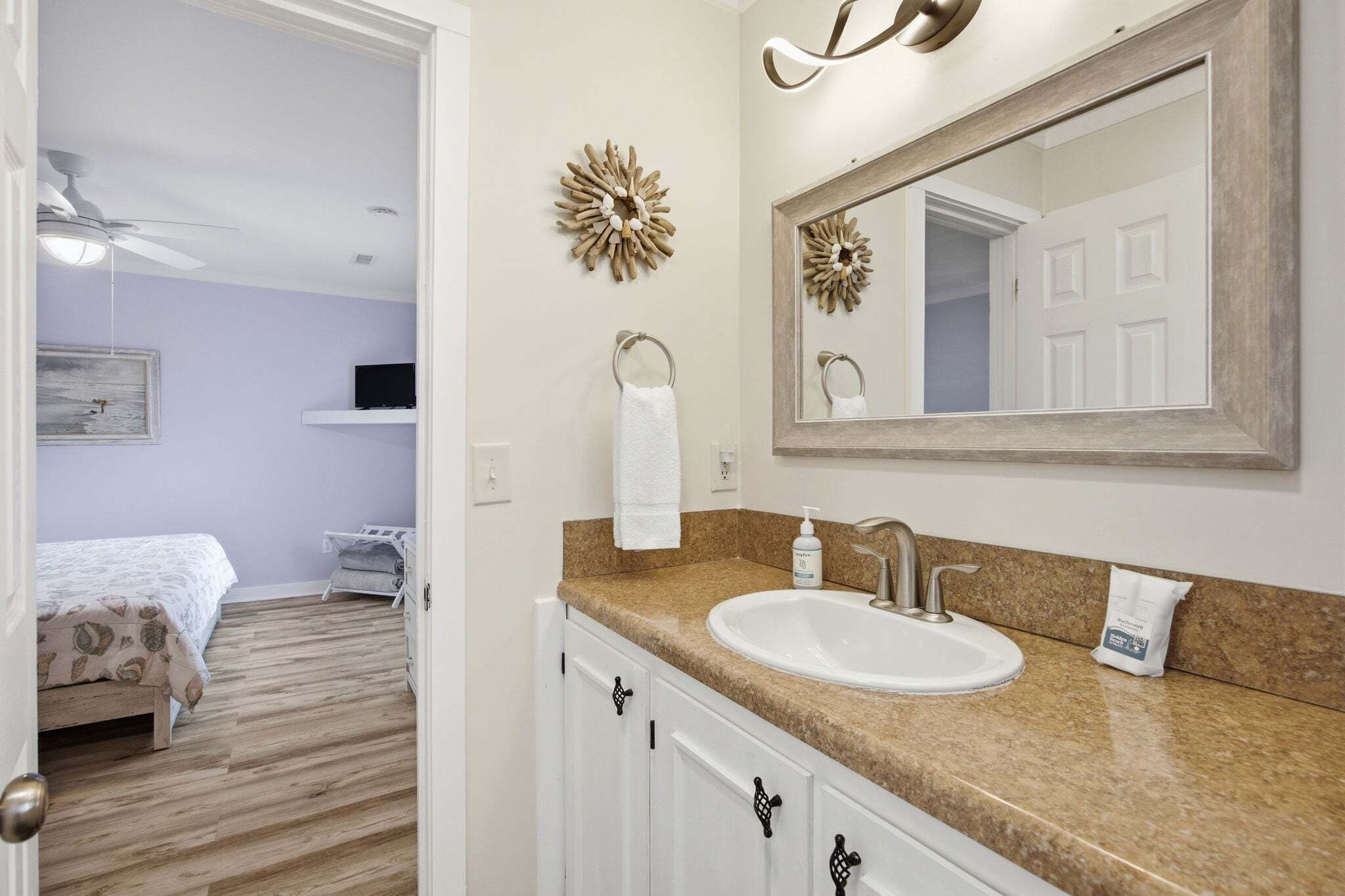 A bathroom with a sink, mirror, towel ring, and decorative wall piece.
