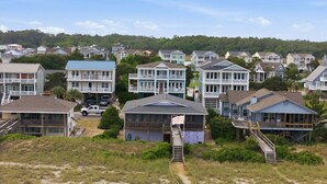 Un quartier résidentiel situé sur la côte, avec des maisons dotées de balcons et une plage de sable au premier plan.