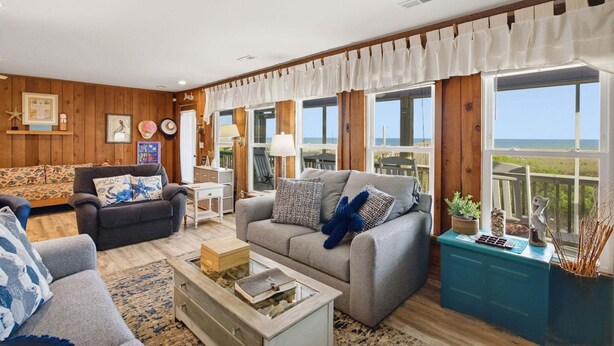 Un salon avec un canapé, des fauteuils, une table basse et une vue sur la mer.