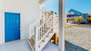 Un bâtiment blanc avec une porte bleue et un escalier blanc menant à un balcon.