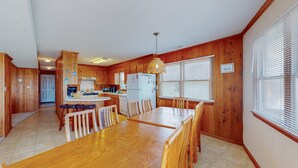 Una cocina amplia con armarios de madera, una gran mesa de comedor y un refrigerador.