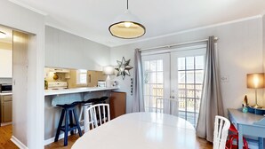 Une cuisine moderne avec une table à manger blanche, des tabourets de bar et un luminaire suspendu.