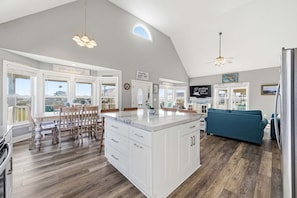 A spacious kitchen with a large island, white cabinetry, and a view of the outdoors.