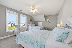 A bedroom with a bed, a dresser, a nightstand, a ceiling fan, and a view of the outside. - Family-Friendly Canal Home - Steps to the Beach (Surf City)