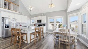 Een moderne keuken met witte kastjes, een roestvrijstalen koelkast, houten stoelen en een eettafel.