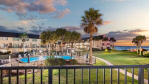 A hotel with a swimming pool, palm trees, and a view of the ocean at sunset. - Home in St Augustine (St. Augustine)