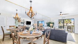 A spacious living room with a dining area, a grey sofa, wooden chairs, a chandelier, and a ceiling fan. - Home in St Augustine (St. Augustine)