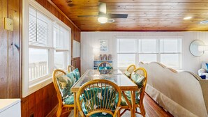 Un coin repas avec une table à plateau en verre, des chaises en osier et un canapé beige.