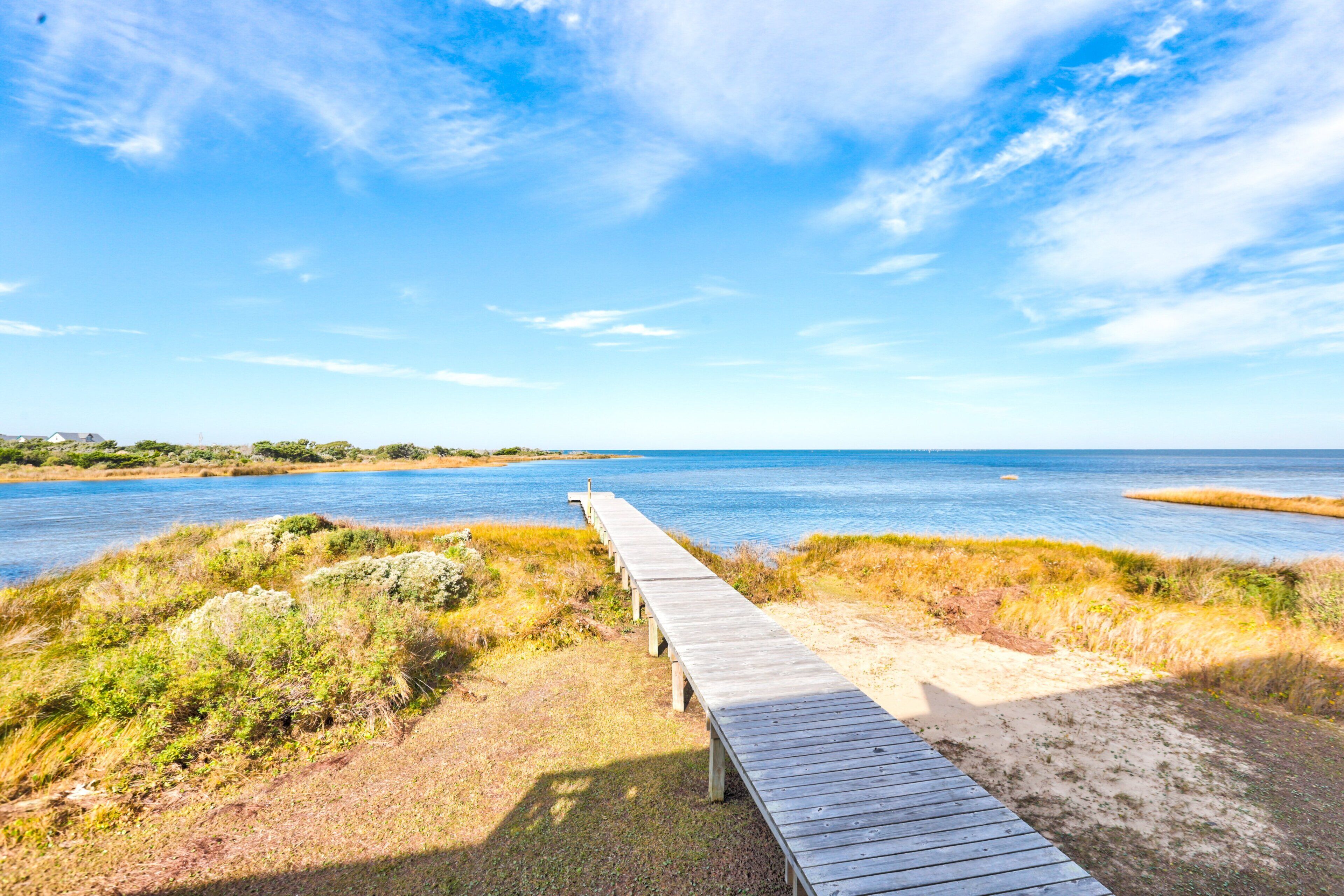 A wooden boardwalk leading to a body of water with a clear sky above.
