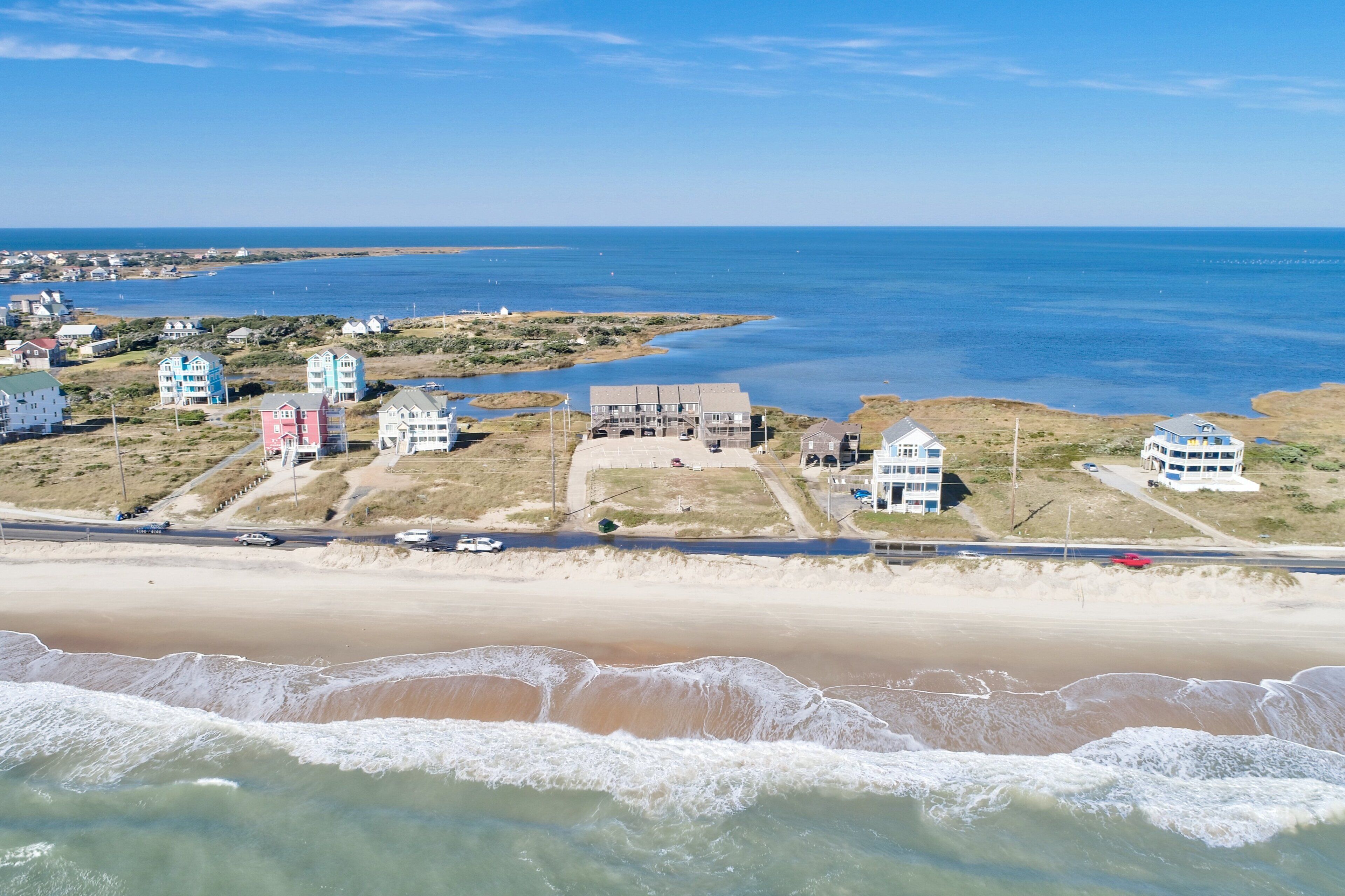 Een kustplaats met woningen aan het strand, een weg en een zandstrand.