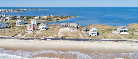 Een kustplaats met woningen aan het strand, een weg en een zandstrand.