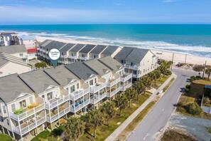 A coastal hotel with multiple-story buildings, balconies, and a view of the beach and ocean.