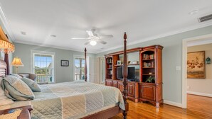 A bedroom with a large bed, a wooden bookcase, and a ceiling fan. - Beautiful Waterway-View Home with Private Pool, Ping-Pong, Washer/Dryer & WiFi (Holden Beach)