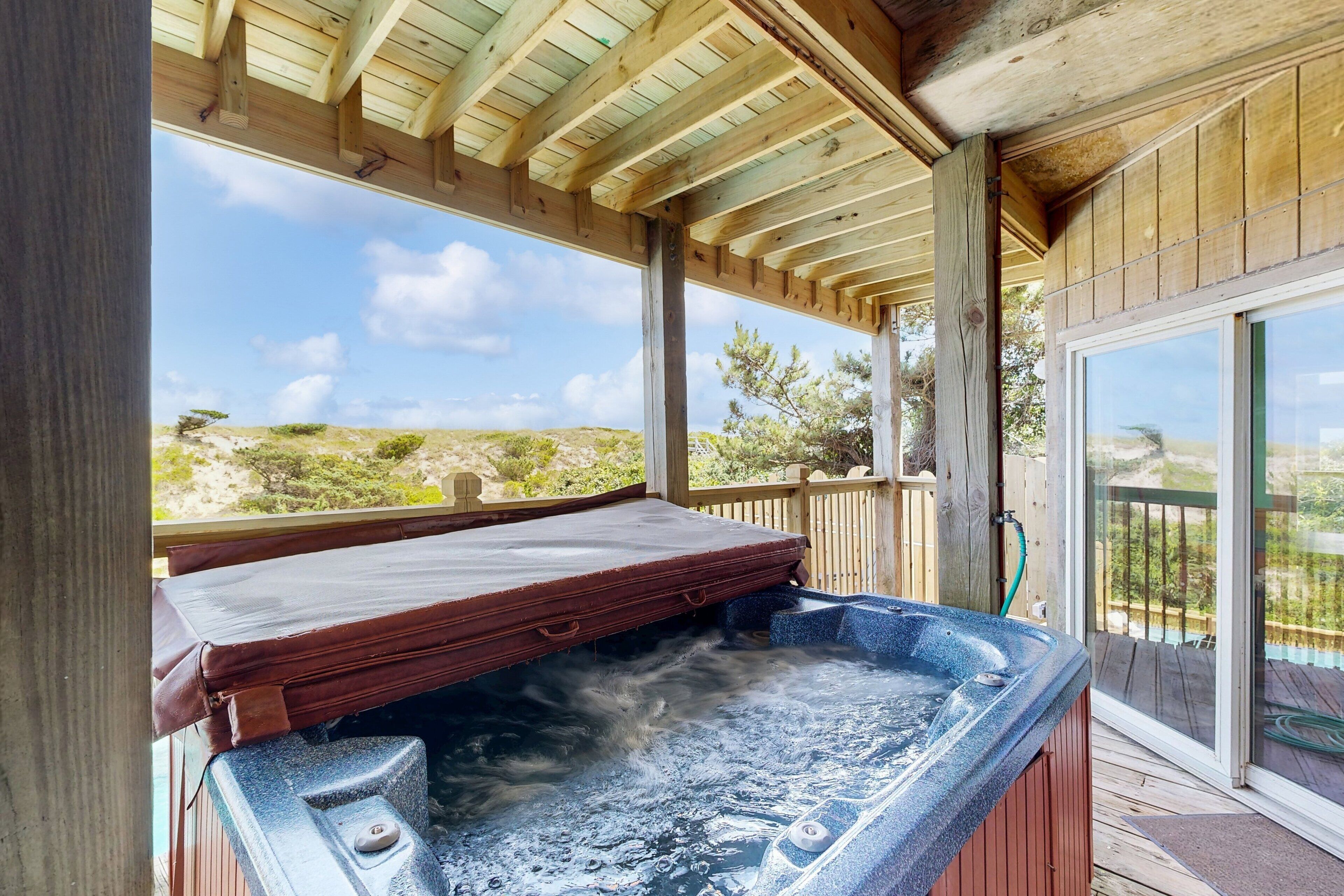 Un jacuzzi bajo una terraza de madera con vista al paisaje.