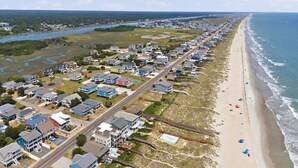 Vista aérea de una zona residencial costera con casas, una playa y una vía de tren.