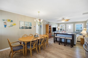 A dining area with a wooden table and chairs, a chandelier, and a ceiling fan.
