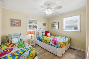 A bedroom with two beds, a ceiling fan, and a window with blinds.