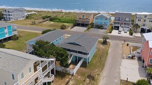 Un área residencial costera con casas, una carretera y el océano al fondo.