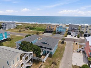 A coastal residential area with houses, a road, and the ocean in the background.