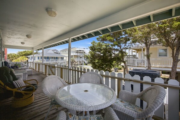 A covered outdoor area with wicker furniture, a round table, and a view of neighboring houses.