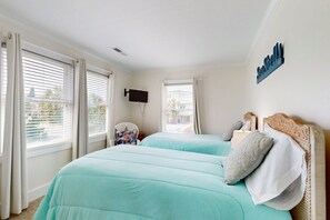 Une chambre d’hôtel avec deux lits, un téléviseur à écran plat, une chaise et un panneau fixé au mur.