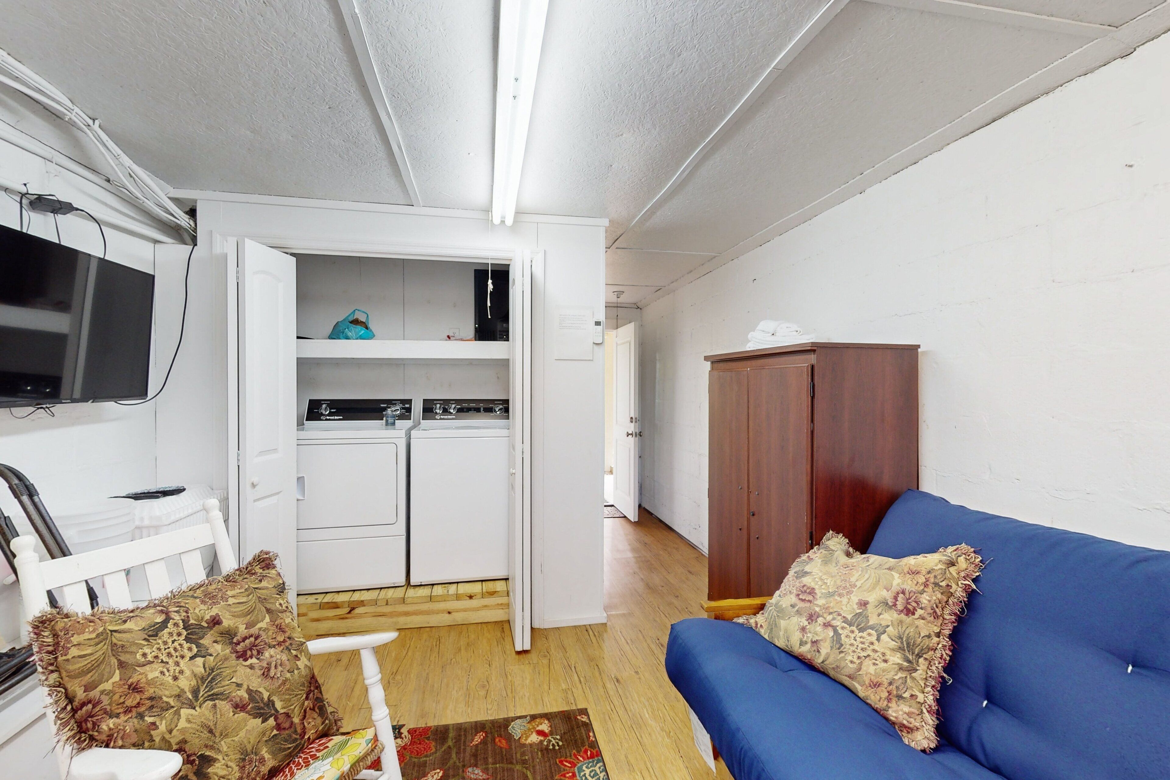 Un espacio habitable pequeño con kitchenette, un sofá azul y un armario de madera.