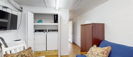 Un espacio habitable pequeño con kitchenette, un sofá azul y un armario de madera.