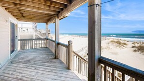 A wooden deck with a railing overlooking a beach. - Prime Time 222: Oceanfront w/outdoor pool, private hot tub, basketball (Avon)