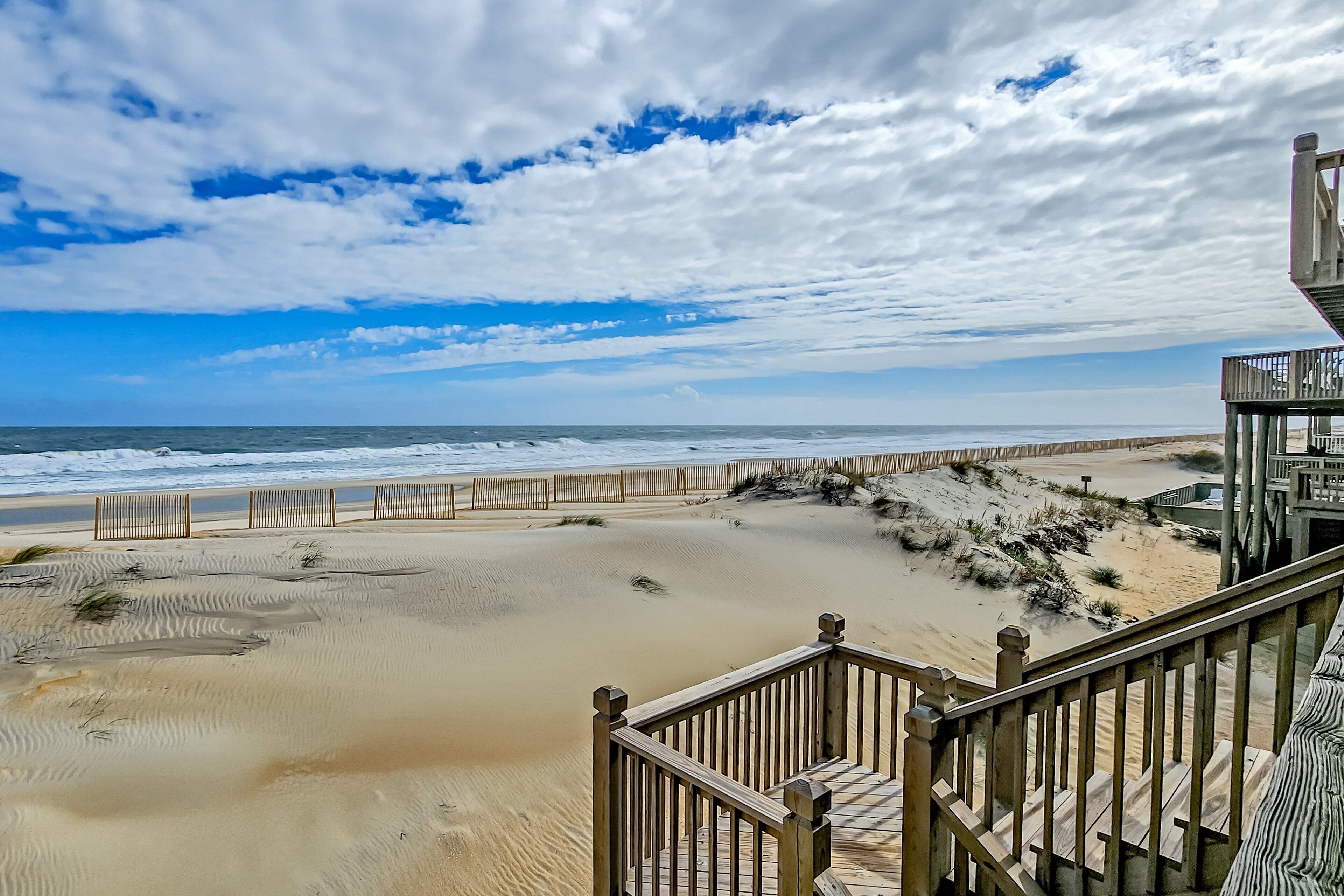 A beach view with a wooden staircase leading to a building.