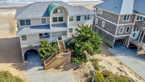 A beachfront property with a two-story house, a covered porch, and a staircase leading to a beach access point. - Prime Time 222: Oceanfront w/outdoor pool, private hot tub, basketball (Avon)