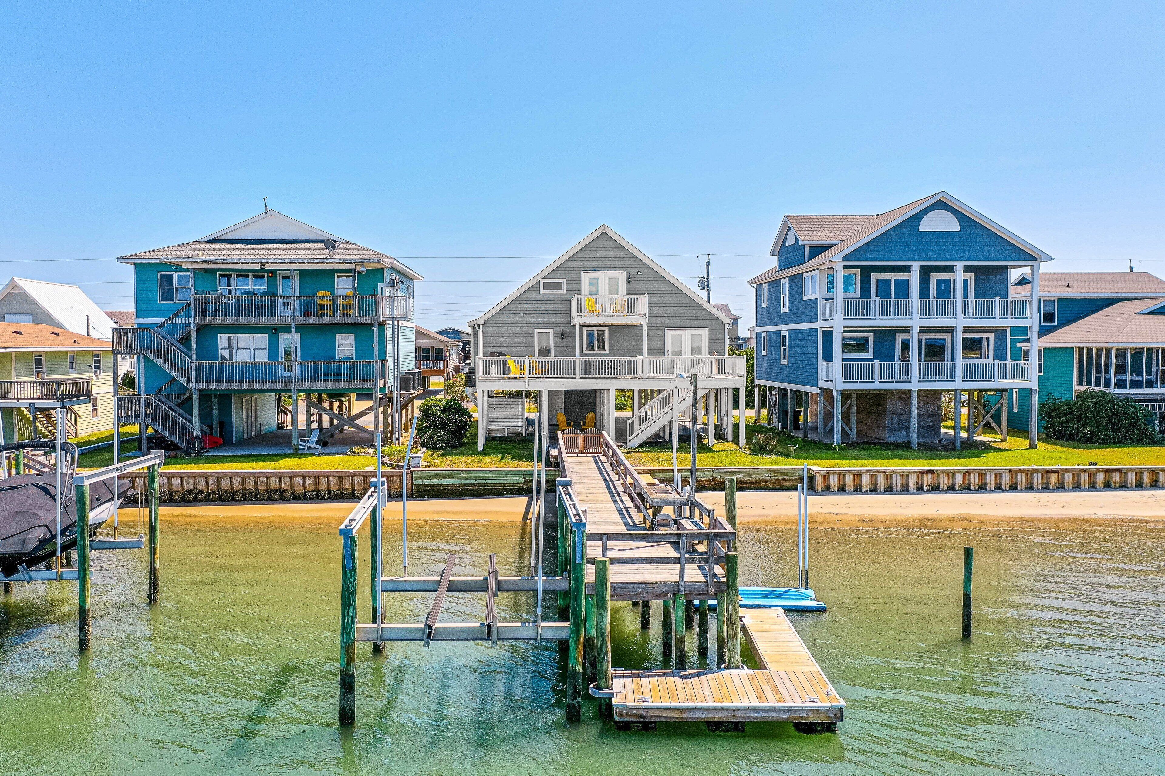 A waterfront property with a dock, a pier, and a house with a balcony.
