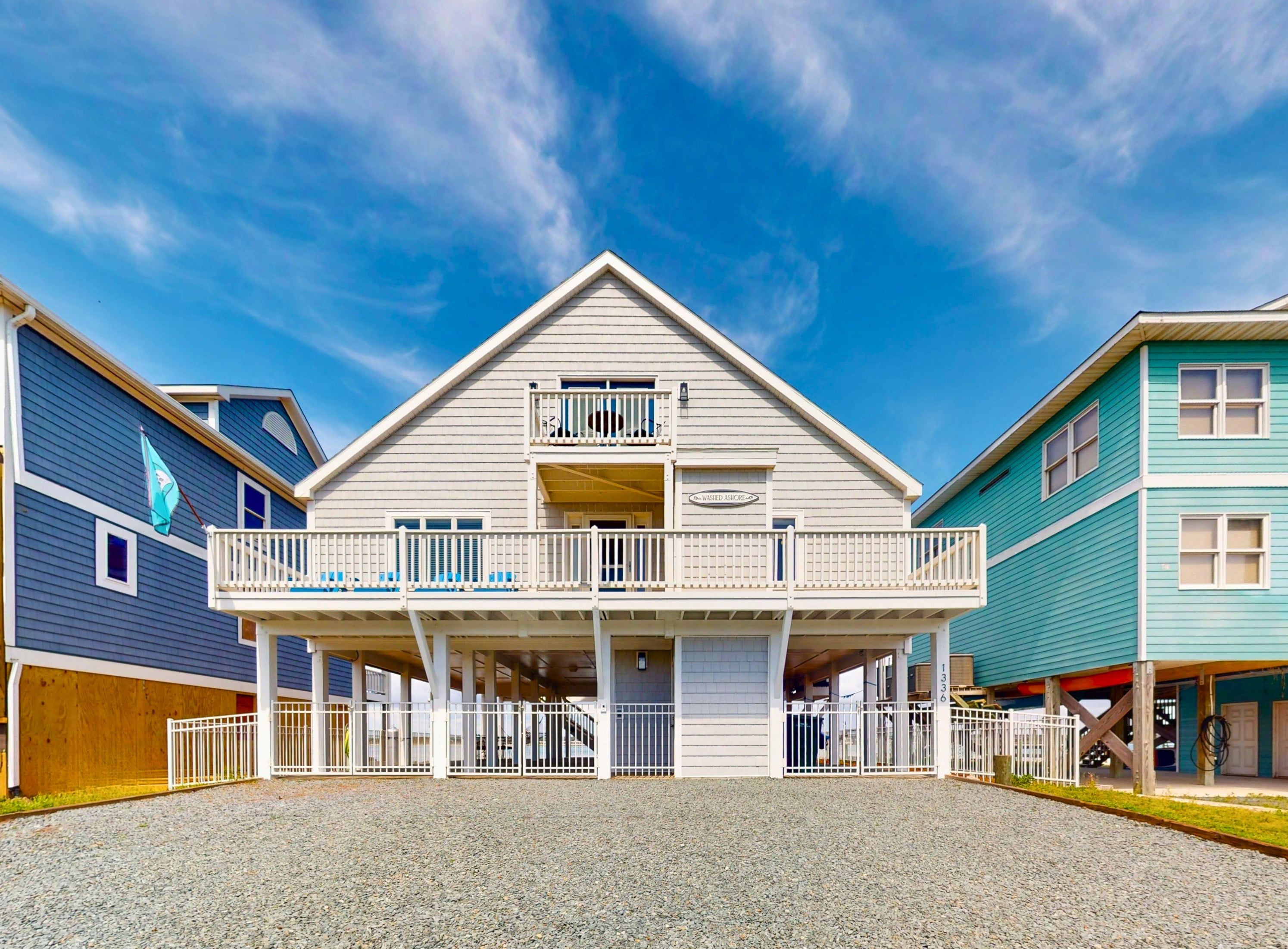 A two-story building with a balcony on the upper floor, a covered front porch, and a gravel driveway.