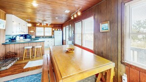 Un intérieur en bois comprenant un coin cuisine, une table à manger en bois et des tabourets de bar.